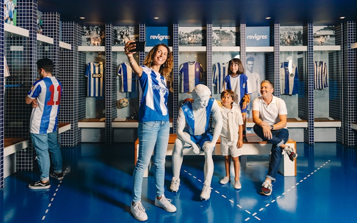 Visitors taking photos at FC Porto museum exhibit with jerseys and statue.