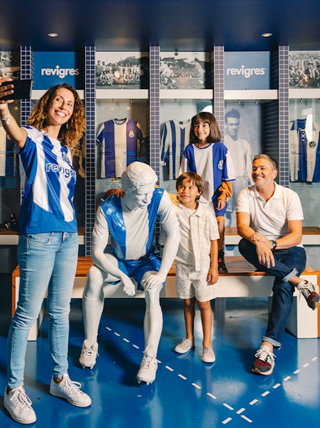 Visitors taking photos at FC Porto museum exhibit with jerseys and statue.