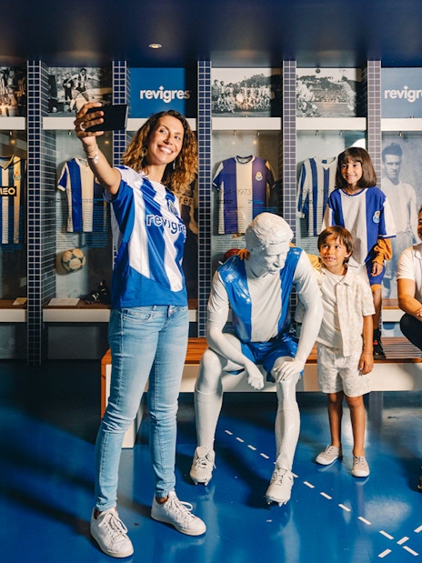 Visitors taking photos at FC Porto museum exhibit with jerseys and statue.