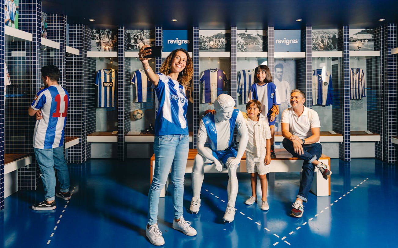 Visitors taking photos at FC Porto museum exhibit with jerseys and statue.