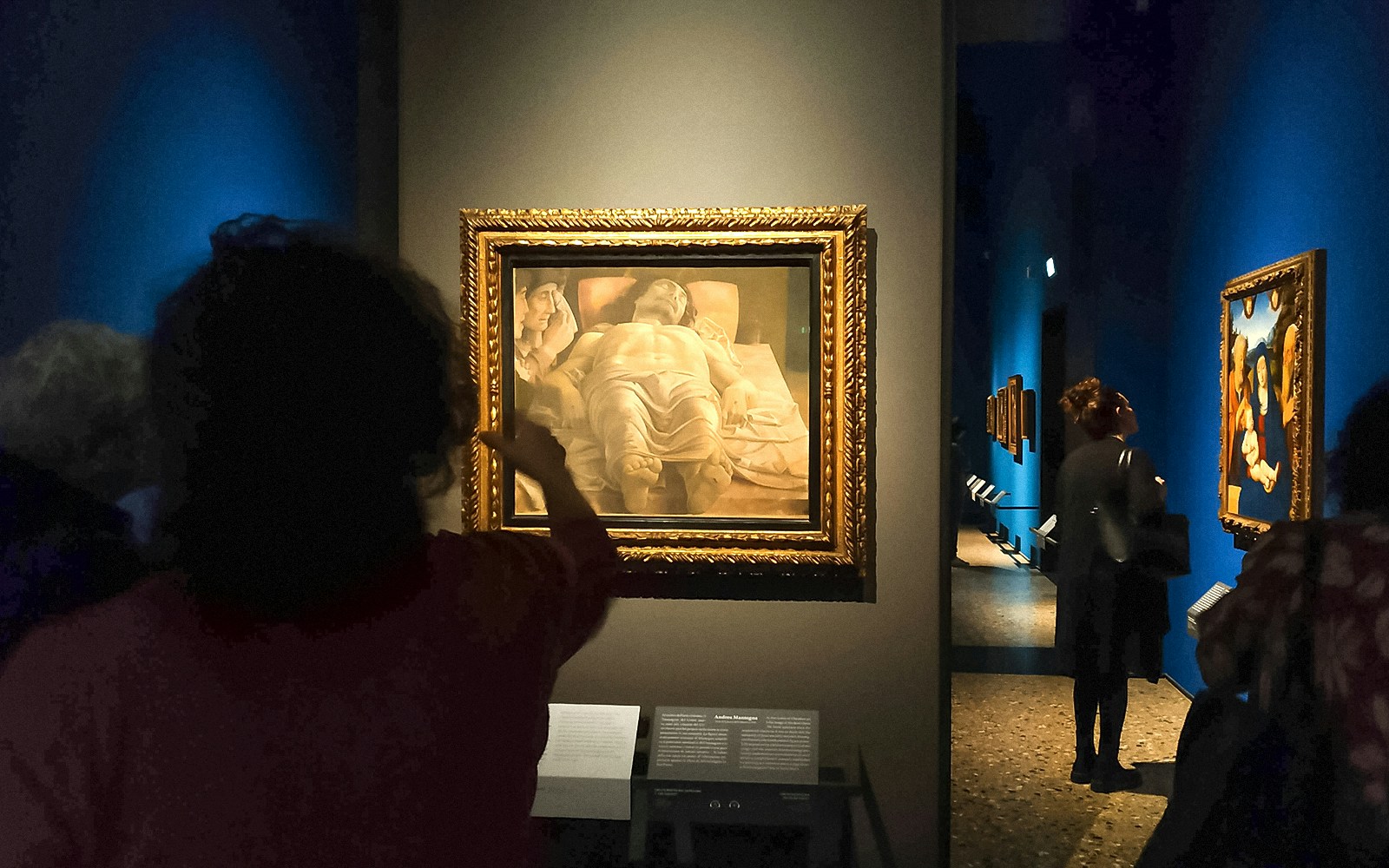 Museum-goers observe and discuss paintings at the Pinacoteca di Brera in Milan, immersed in the art experience.