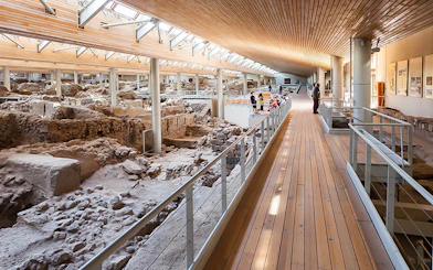 Visitors walking along a wooden walkway inside Akrotiri Excavations, Santorini.