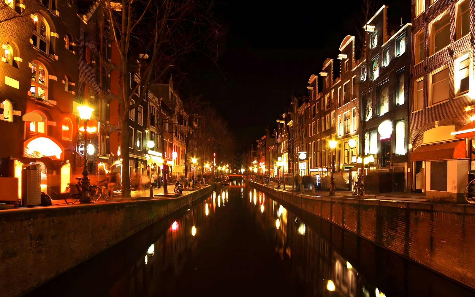 Amsterdam canal with illuminated bridges during evening cruise.