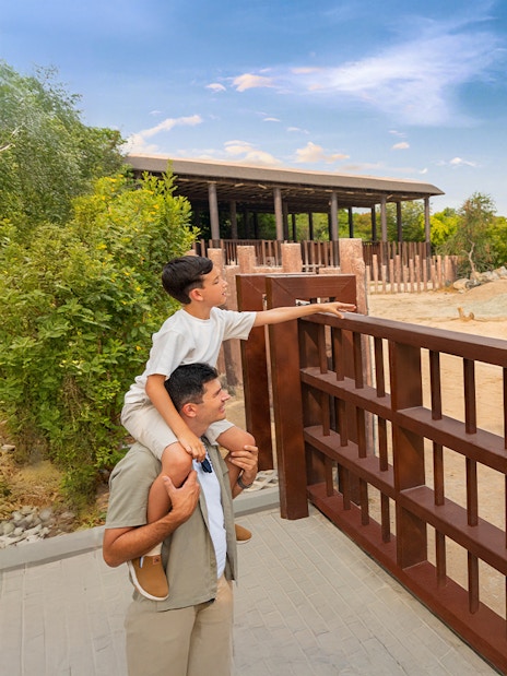 Father and son observing an elephant at Dubai Safari Park.