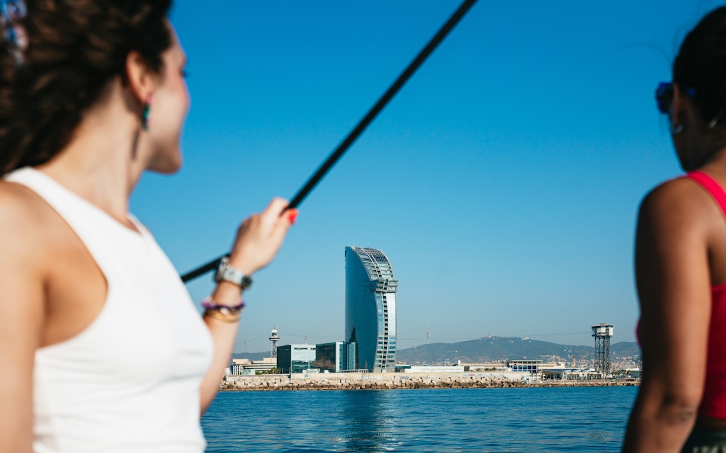 Friends enjoying a view of the W Barcelona Hotel from a sailing yacht on a Barcelona sightseeing cruise.