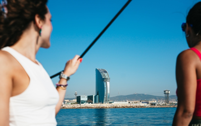 Friends enjoying a view of the W Barcelona Hotel from a sailing yacht on a Barcelona sightseeing cruise.