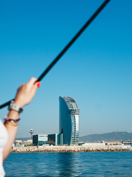 Friends enjoying a view of the W Barcelona Hotel from a sailing yacht on a Barcelona sightseeing cruise.
