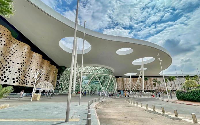 Marrakech Menara Airport entrance with modern architecture and travelers outside.