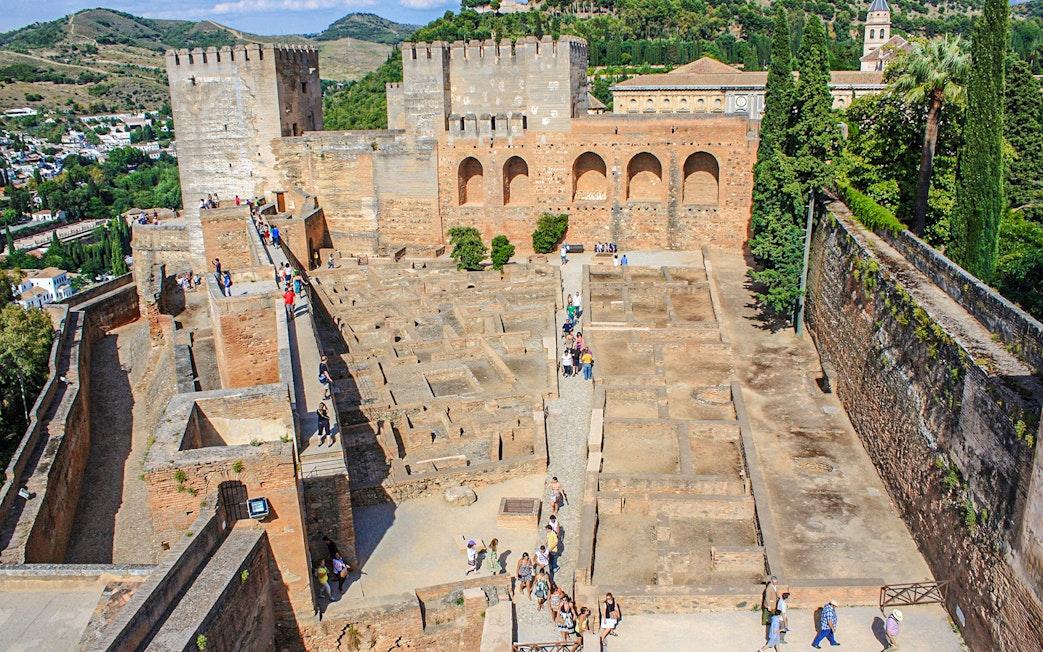 Visitors exploring the ancient walls and ruins of the Alhambra complex in Granada, Spain.
