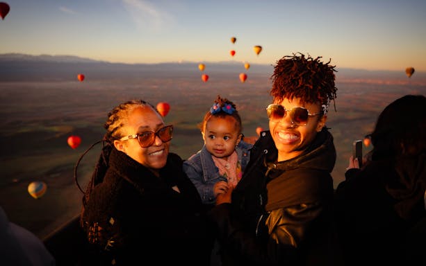 Family enjoying hot air balloon flight over Marrakech landscape.