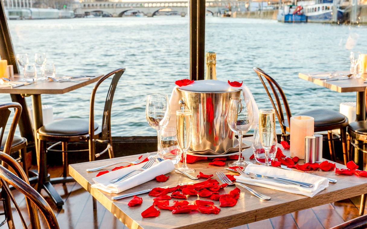 Table set with champagne and rose petals on Seine River cruise.