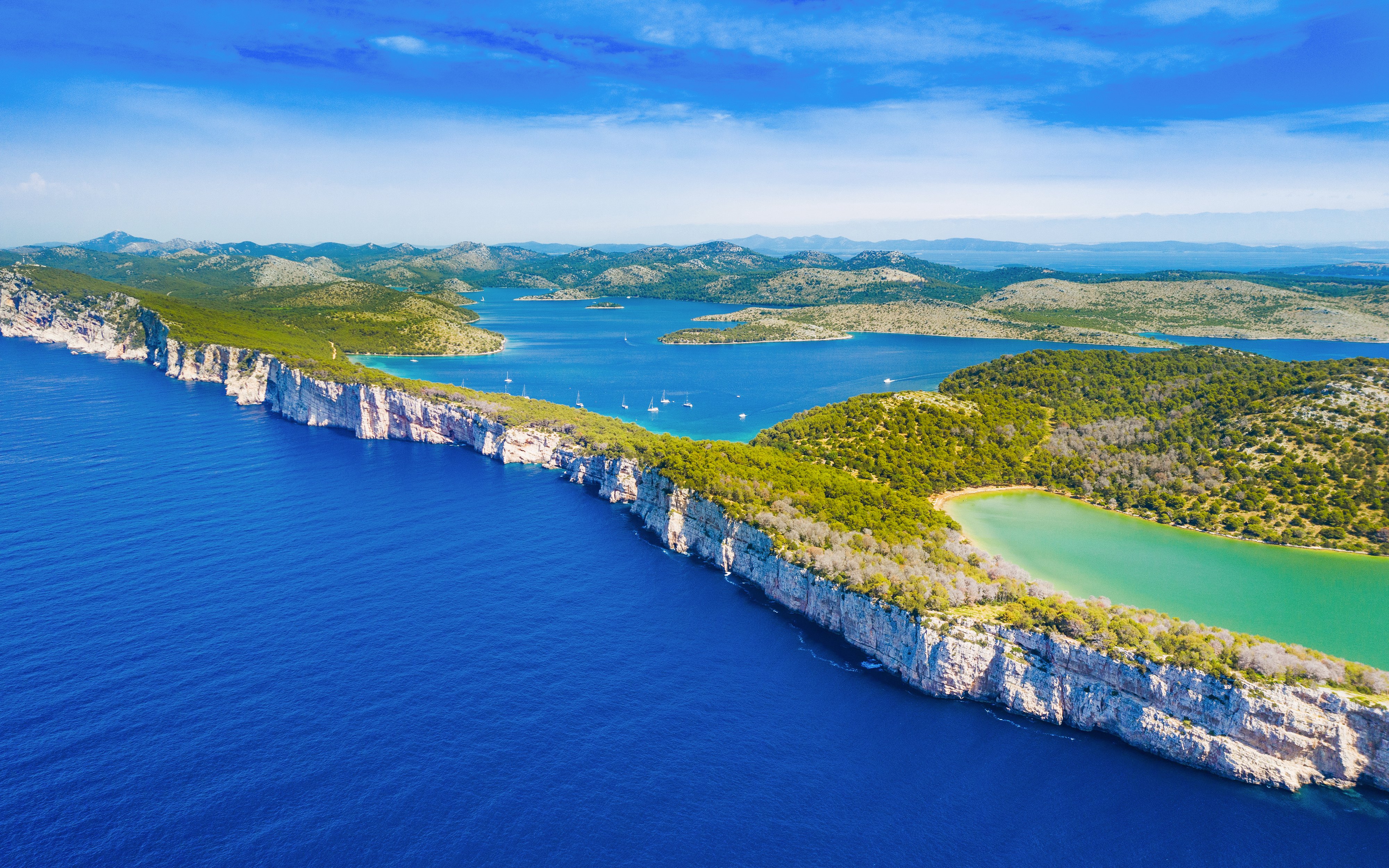 Cliffs above the sea in Telascica Nature Park, Dugi Otok, Croatia, with lush greenery and blue waters.