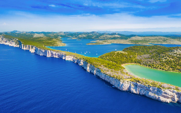 Cliffs above the sea in Telascica Nature Park, Dugi Otok, Croatia, with lush greenery and blue waters.