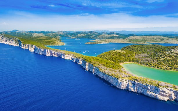Cliffs above the sea in Telascica Nature Park, Dugi Otok, Croatia, with lush greenery and blue waters.