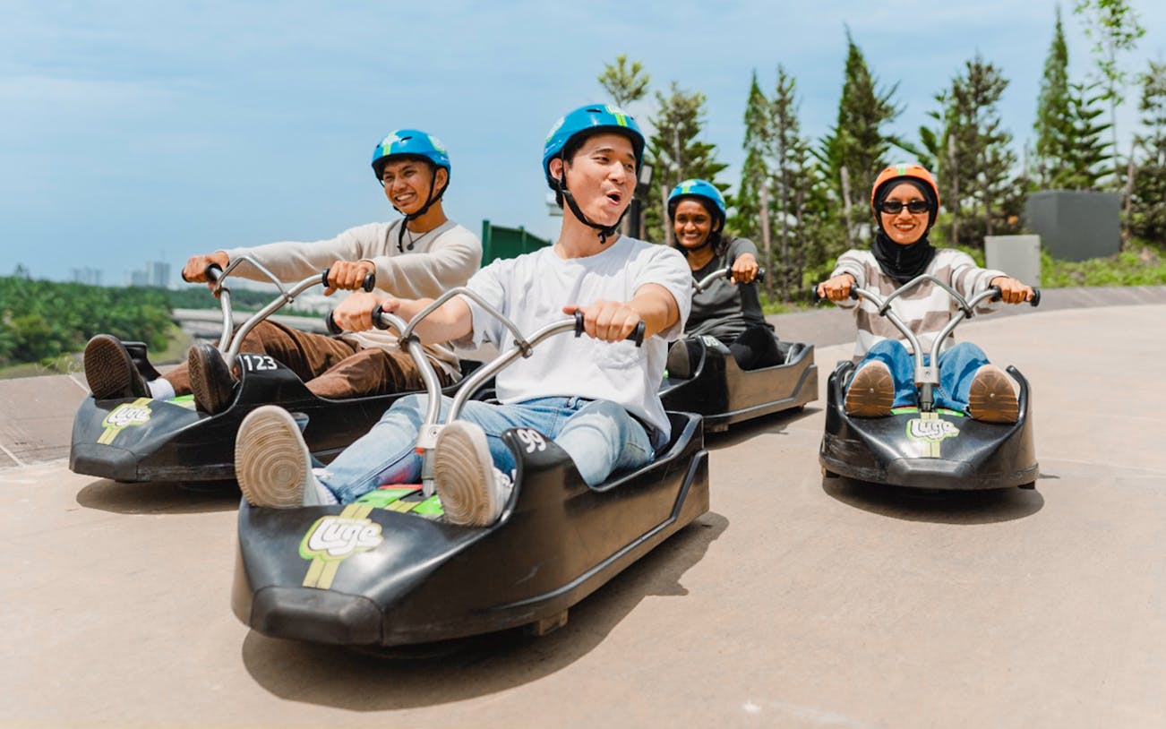 Skyline Luge track with riders in Kuala Lumpur, Malaysia, cityscape in the background.