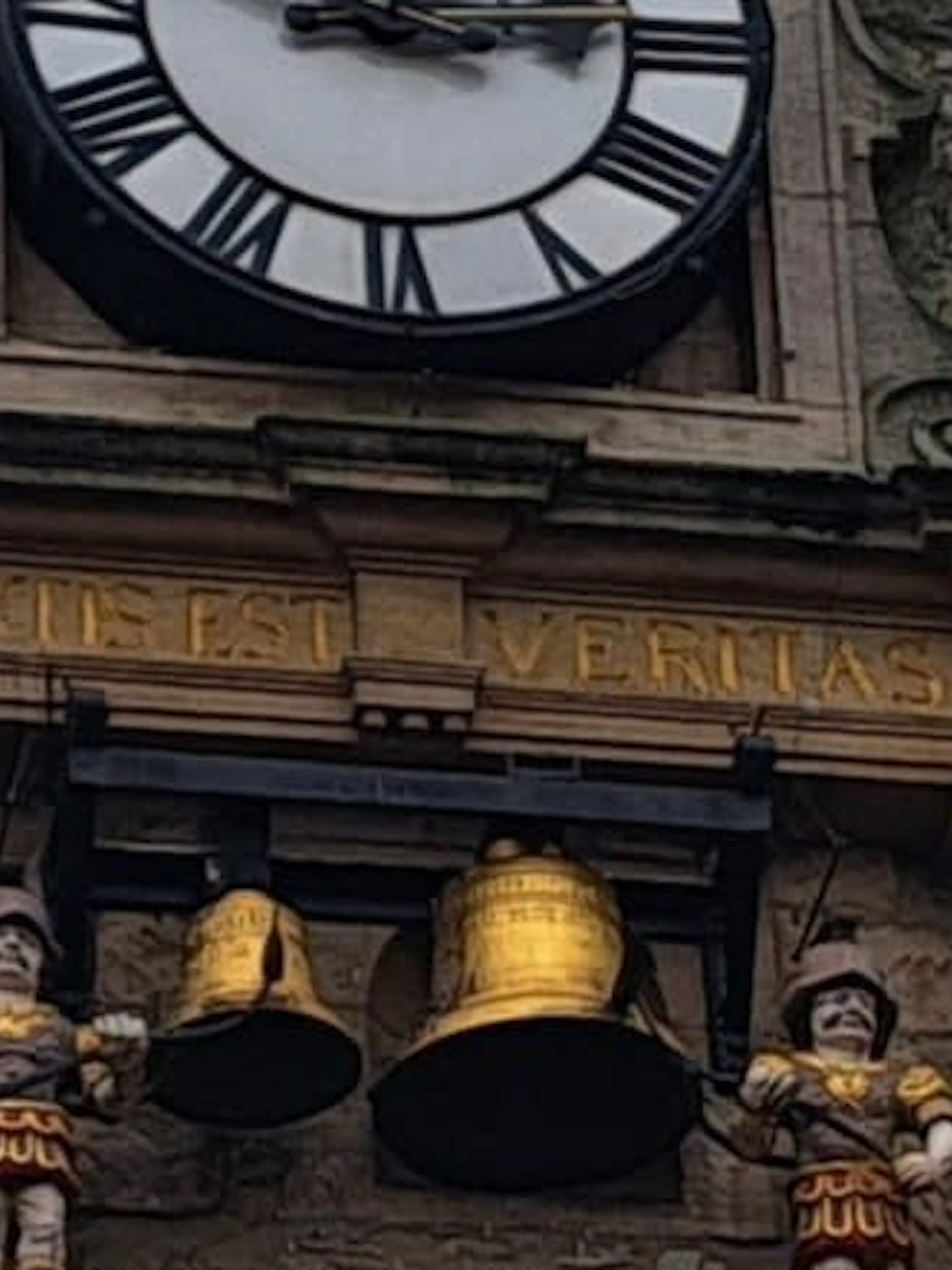 Oxford clock tower with Latin inscription and figures, part of self-guided city exploration game.
