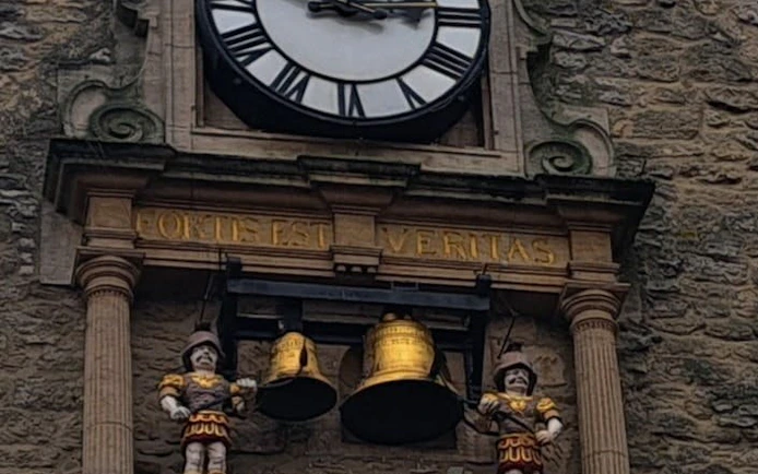 Oxford clock tower with Latin inscription and figures, part of self-guided city exploration game.