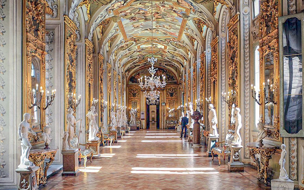 Doria Pamphilj Gallery hall with ornate ceiling, chandeliers, and classical statues.