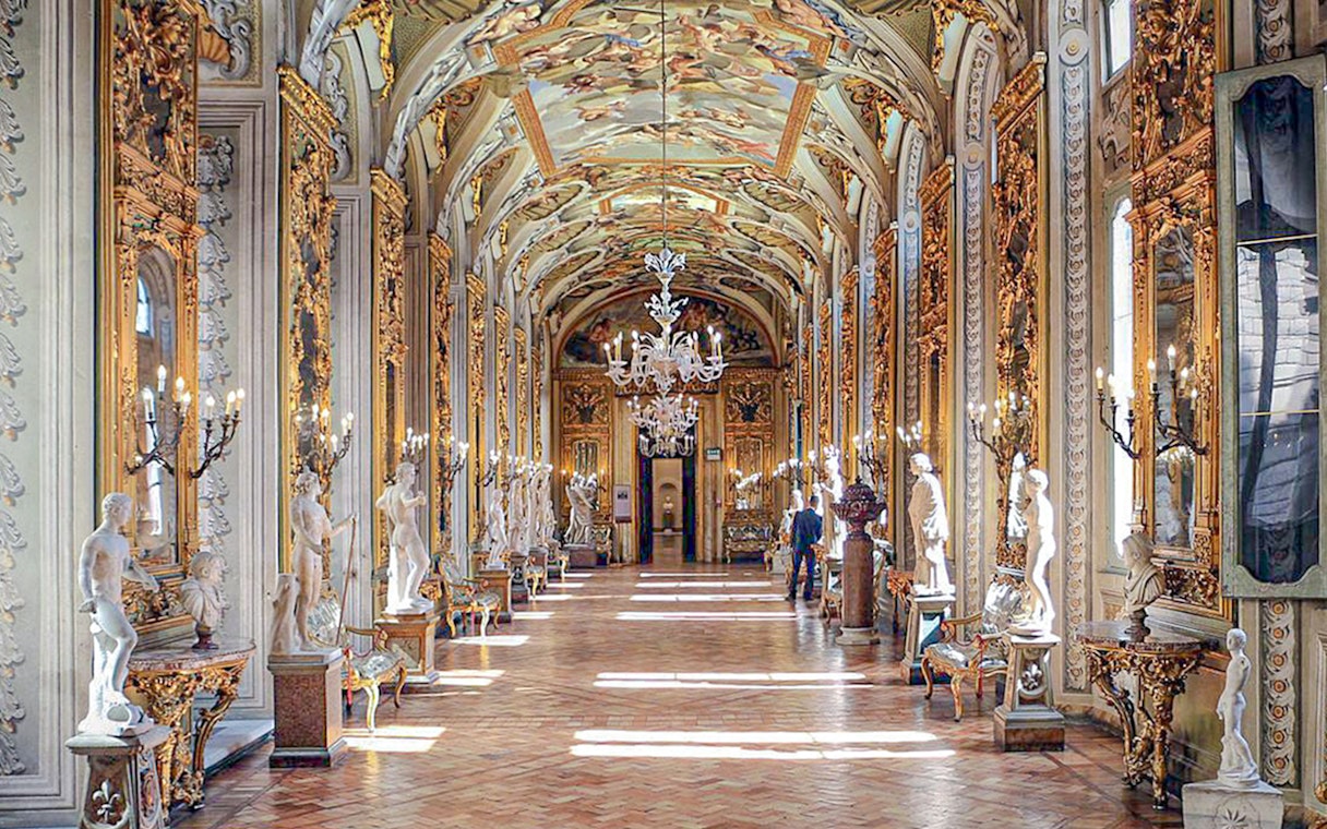 Doria Pamphilj Gallery hall with ornate ceiling, chandeliers, and classical statues.
