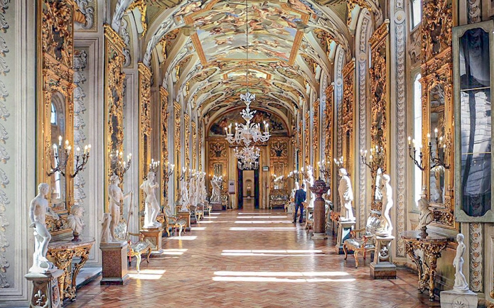Doria Pamphilj Gallery hall with ornate ceiling, chandeliers, and classical statues.