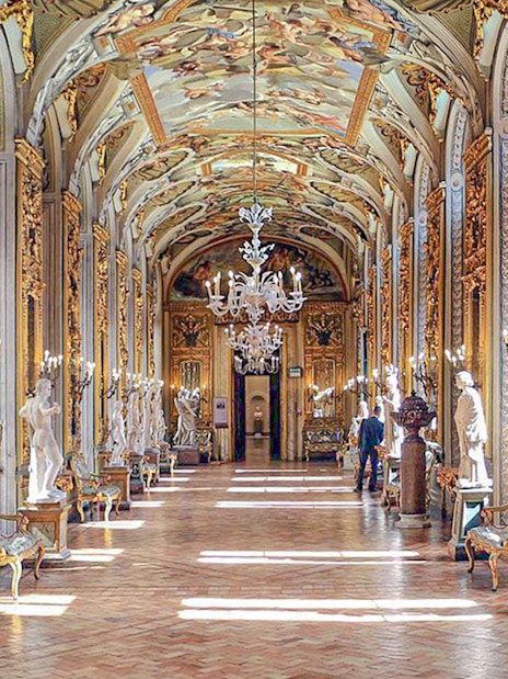 Doria Pamphilj Gallery hall with ornate ceiling, chandeliers, and classical statues.