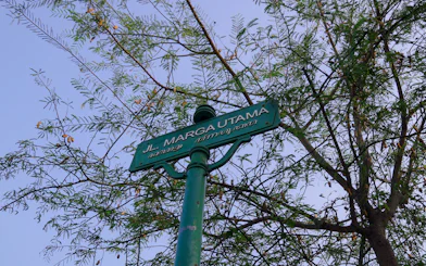 Street sign for Jl. Marga Utama with tree branches, part of Colonial Heritage Walking Tour, Yogyakarta.