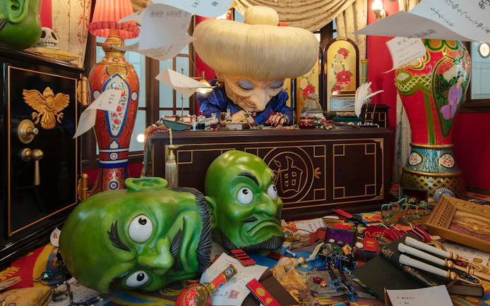 Director's Room with ornate desk, large green masks, and colorful decor.