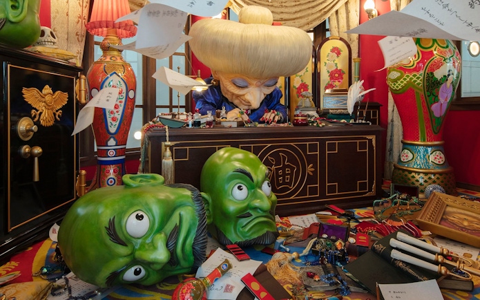 Director's Room with ornate desk, large green masks, and colorful decor.