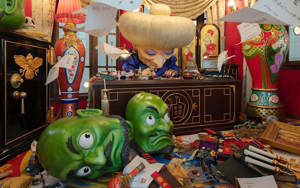 Director's Room with ornate desk, large green masks, and colorful decor.