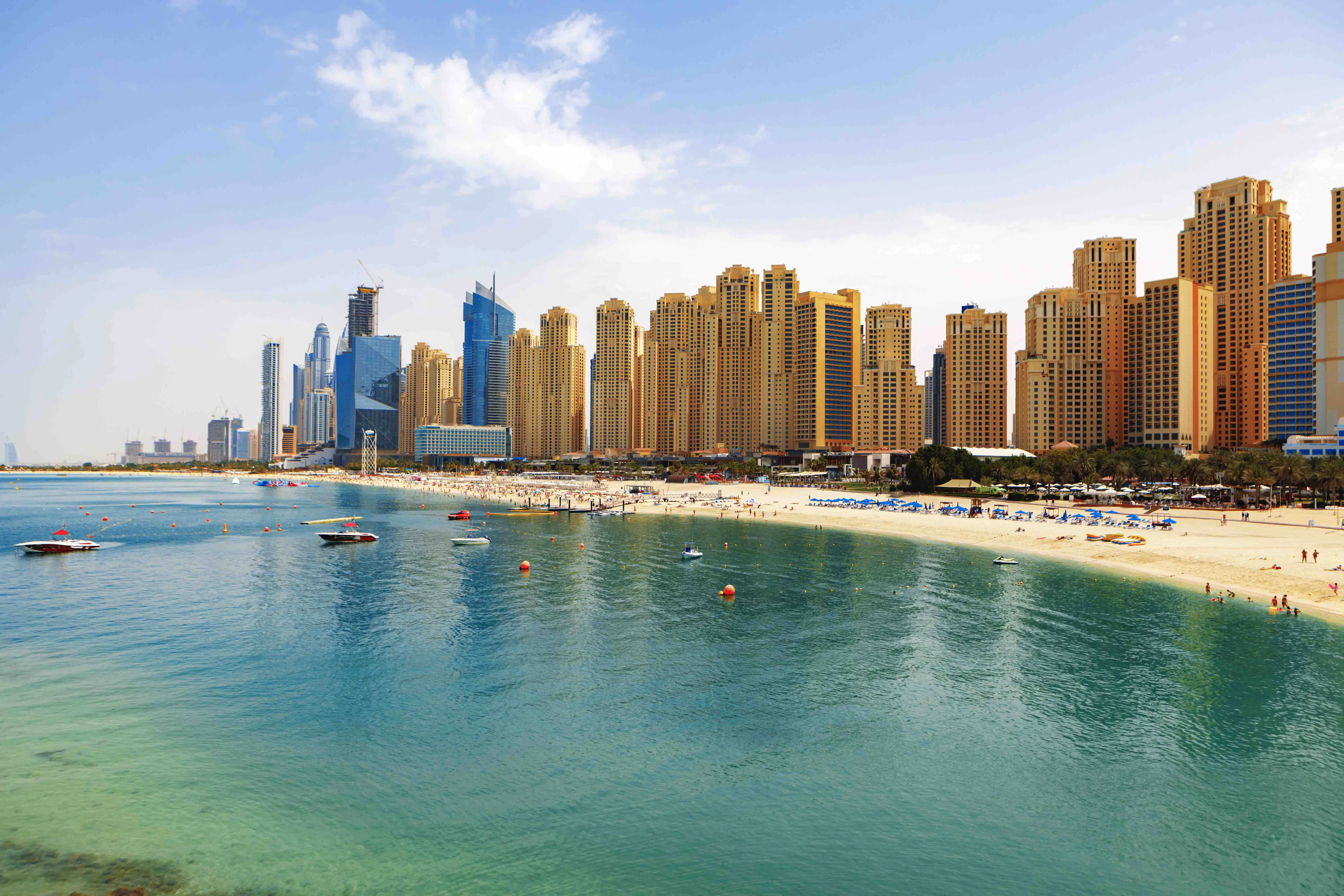 Jumeirah Beach Residences skyline with beach and boats in Dubai.