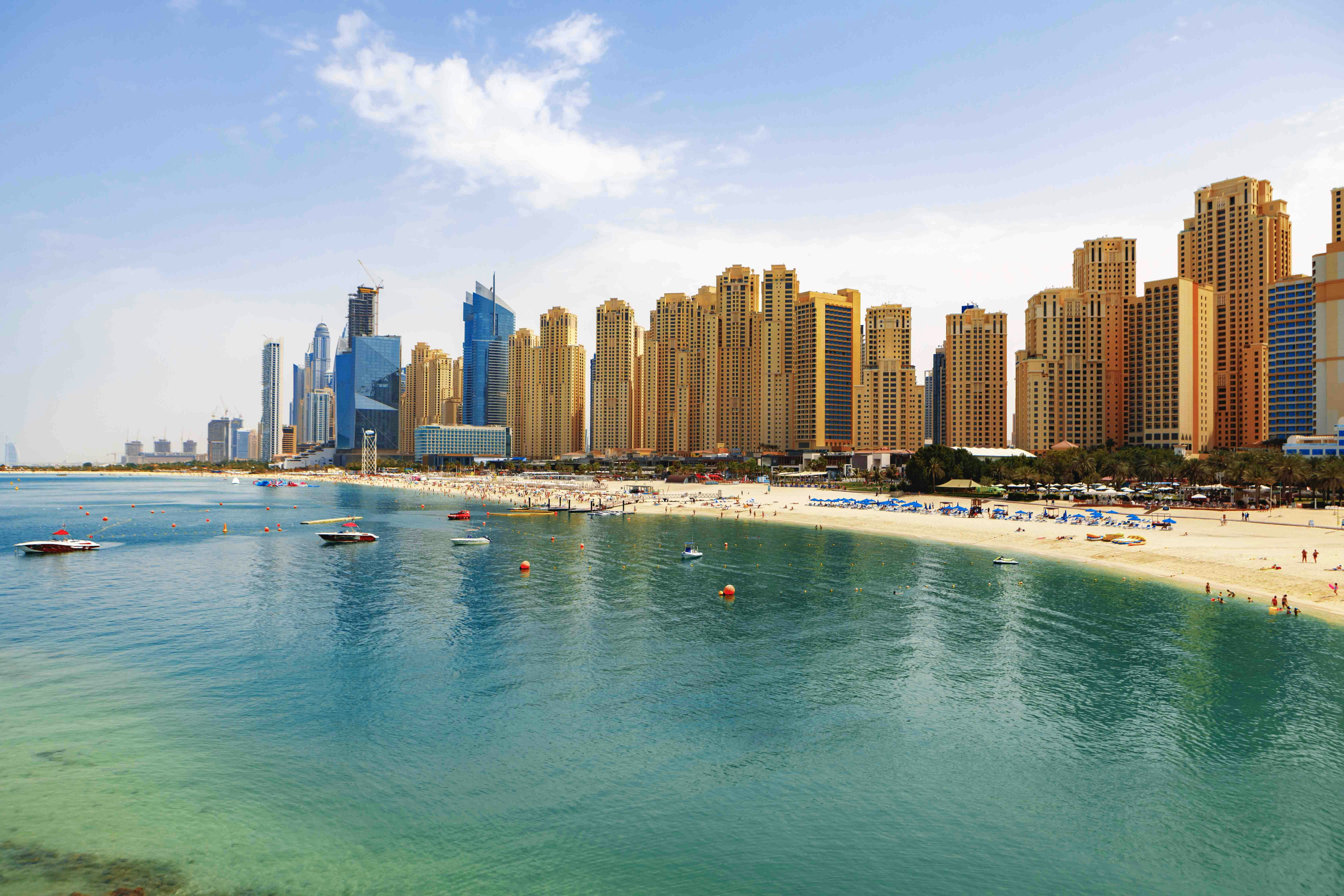 Jumeirah Beach Residences skyline with beach and boats in Dubai.