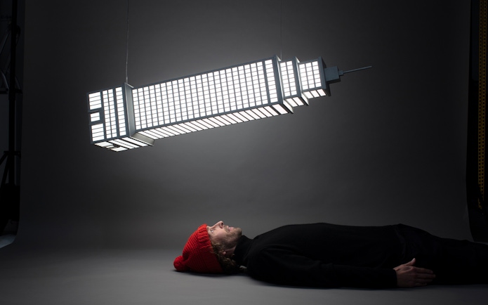 Man lying beneath illuminated sculpture at Amsterdam Moco Museum's Planet Positive Disruption exhibit by Frankey.
