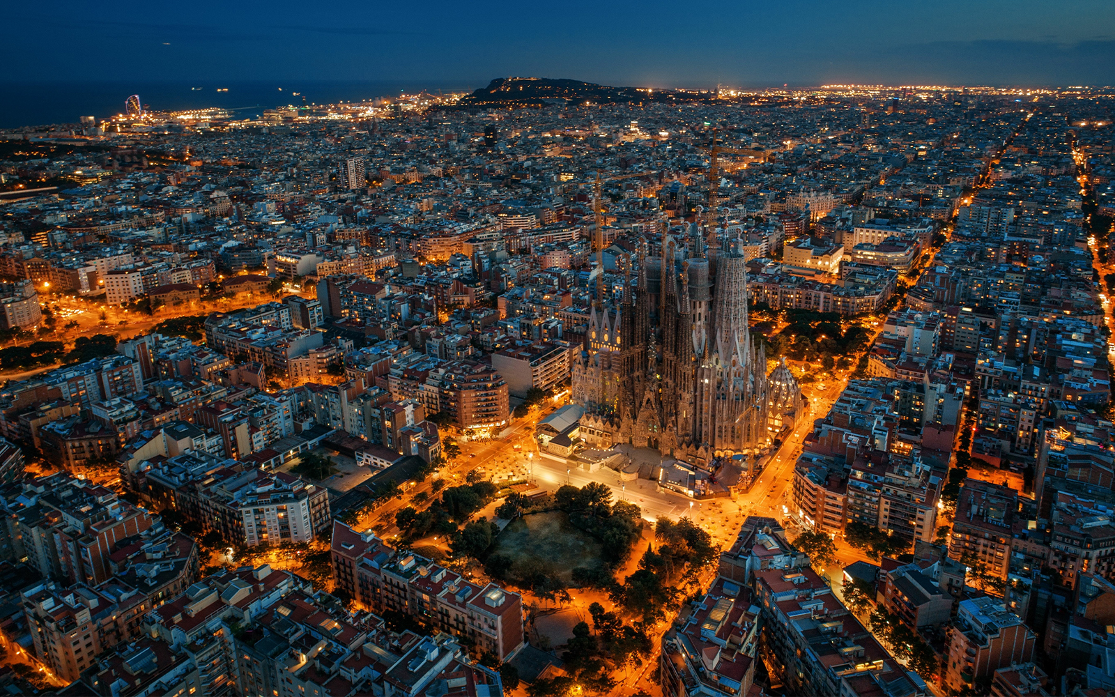 Sagrada Familia illuminated at night, aerial view over Barcelona.