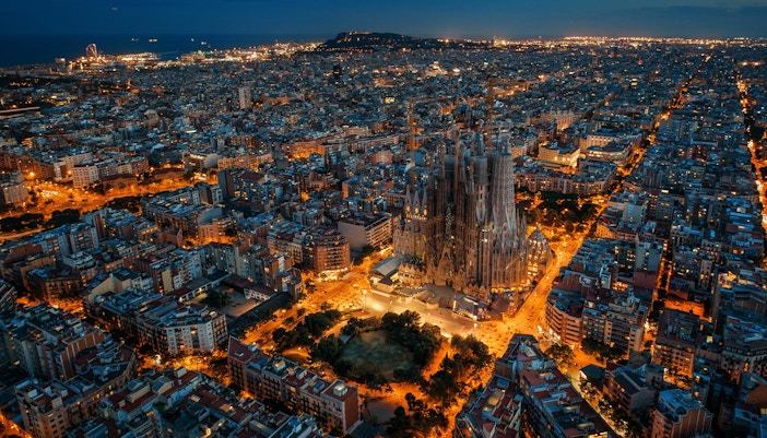 Sagrada Familia illuminated at night, aerial view over Barcelona.