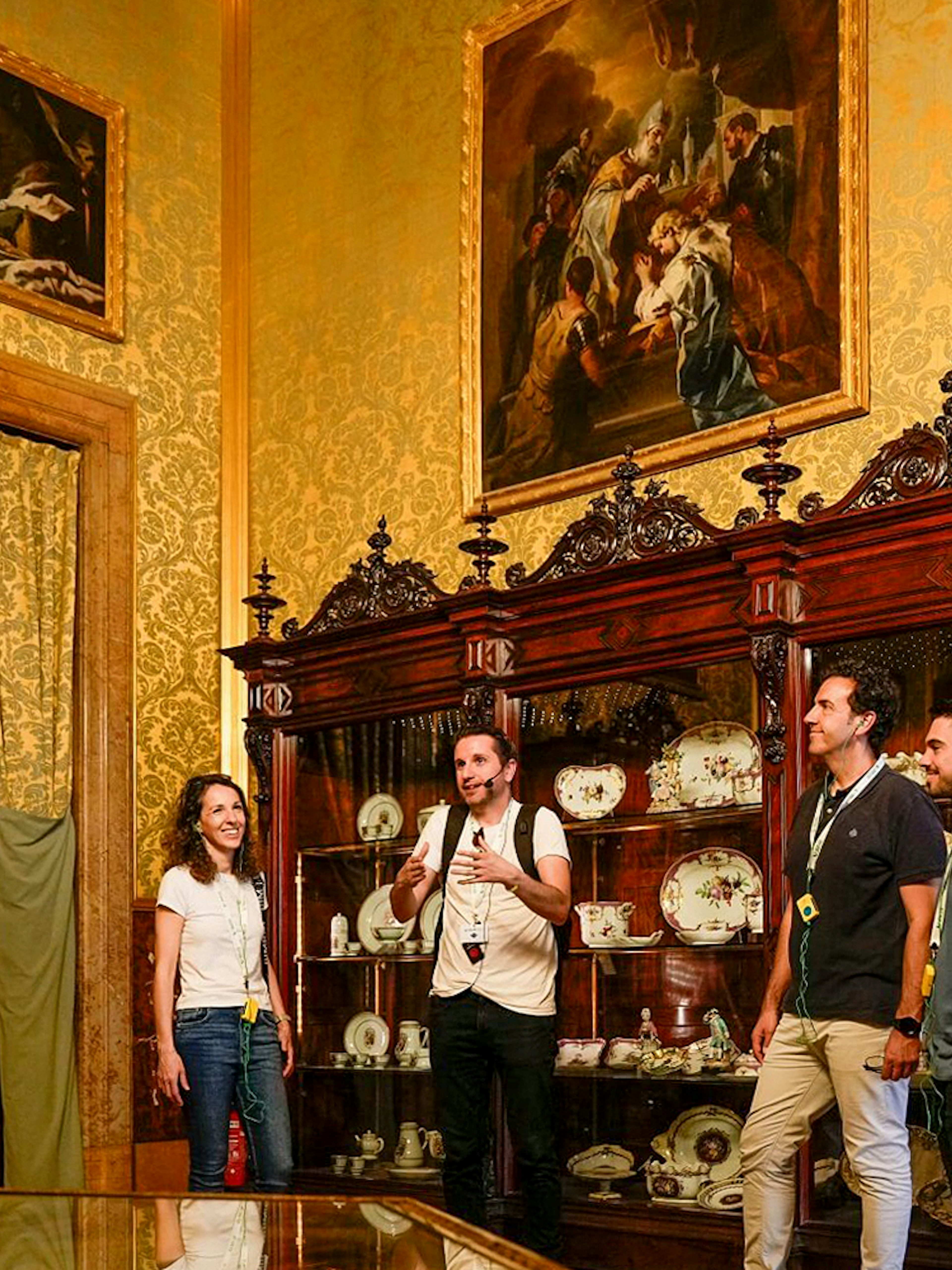 Tour group exploring the Royal Palace of Madrid's ornate room with guide.