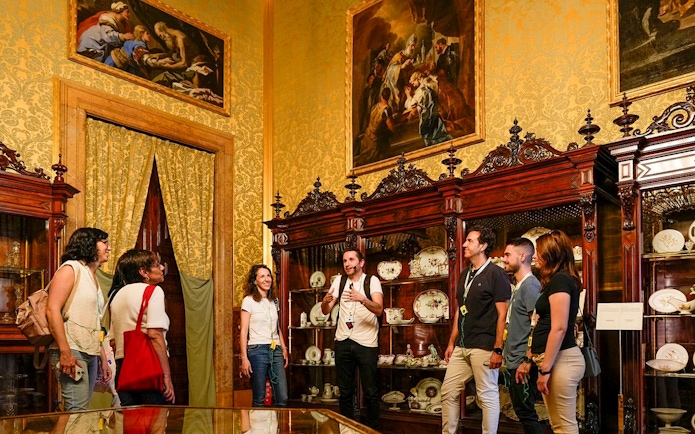 Tour group exploring the Royal Palace of Madrid's ornate room with guide.