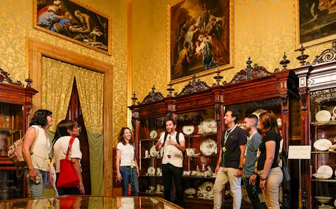 Tour group exploring the Royal Palace of Madrid's ornate room with guide.