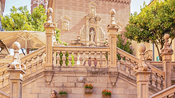Visitor walking near historic architecture in Poble Espanyol, Barcelona.