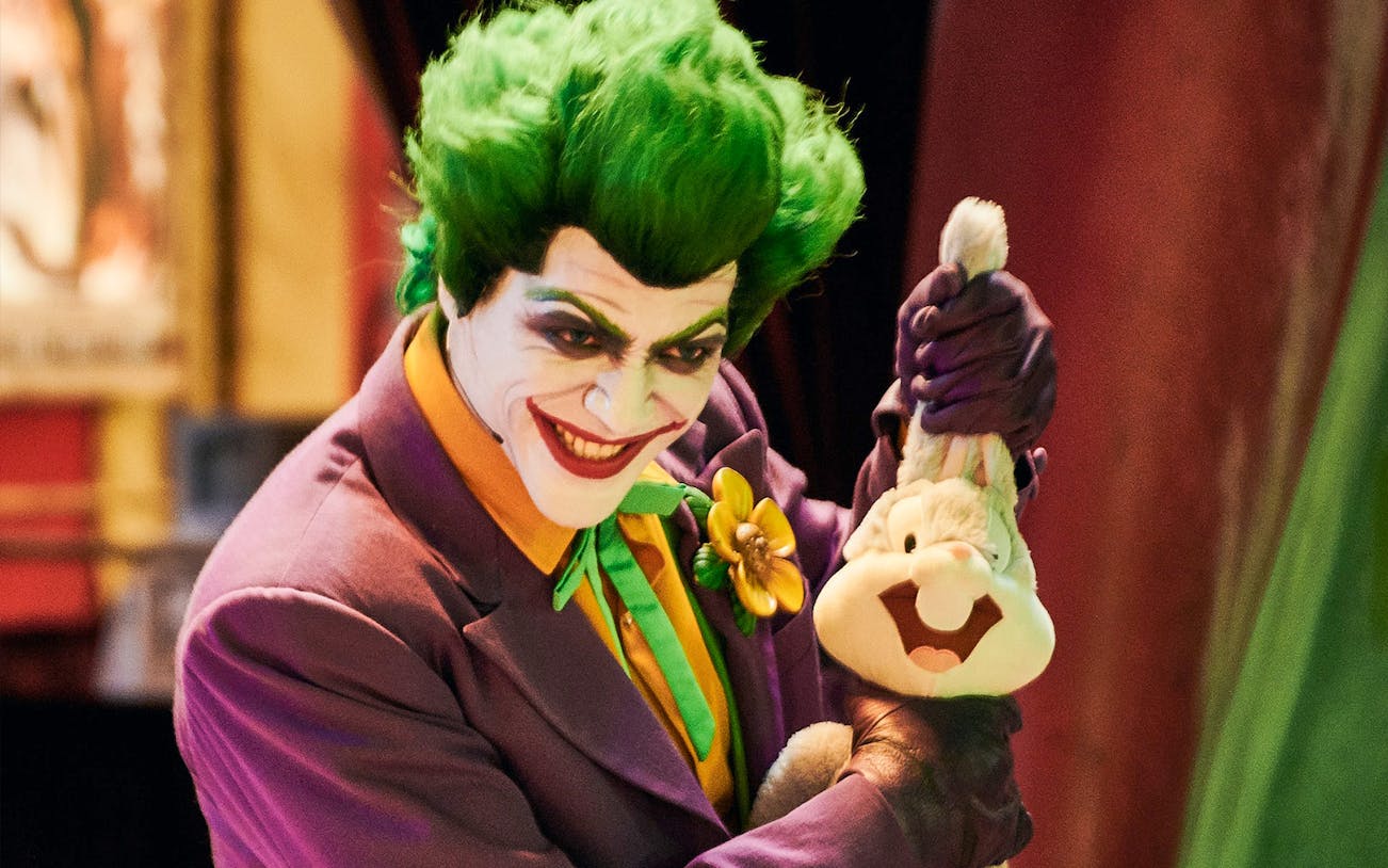 Character in colorful costume holding a plush toy at Warner Bros. World Abu Dhabi.