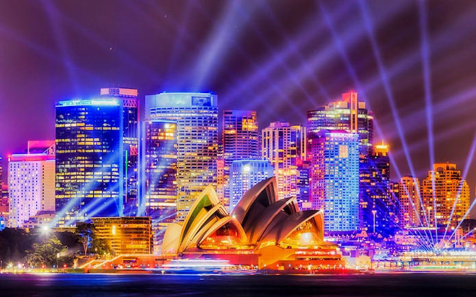 Sydney Opera House illuminated during Vivid Sydney festival with city skyline.