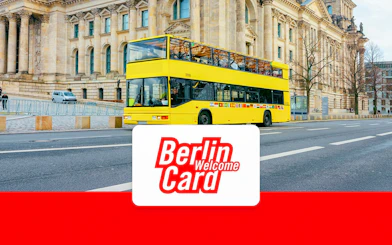 Yellow double-decker bus in front of Berlin landmark with Berlin Welcome Card logo.