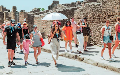 Tour group exploring ancient ruins in Pompeii with guide.