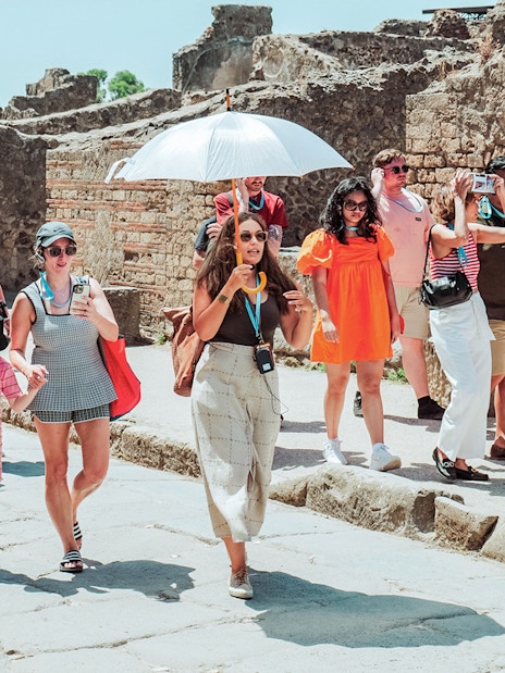 Tour group exploring ancient ruins in Pompeii with guide.