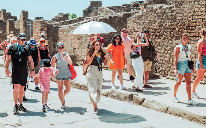 Tour group exploring ancient ruins in Pompeii with guide.