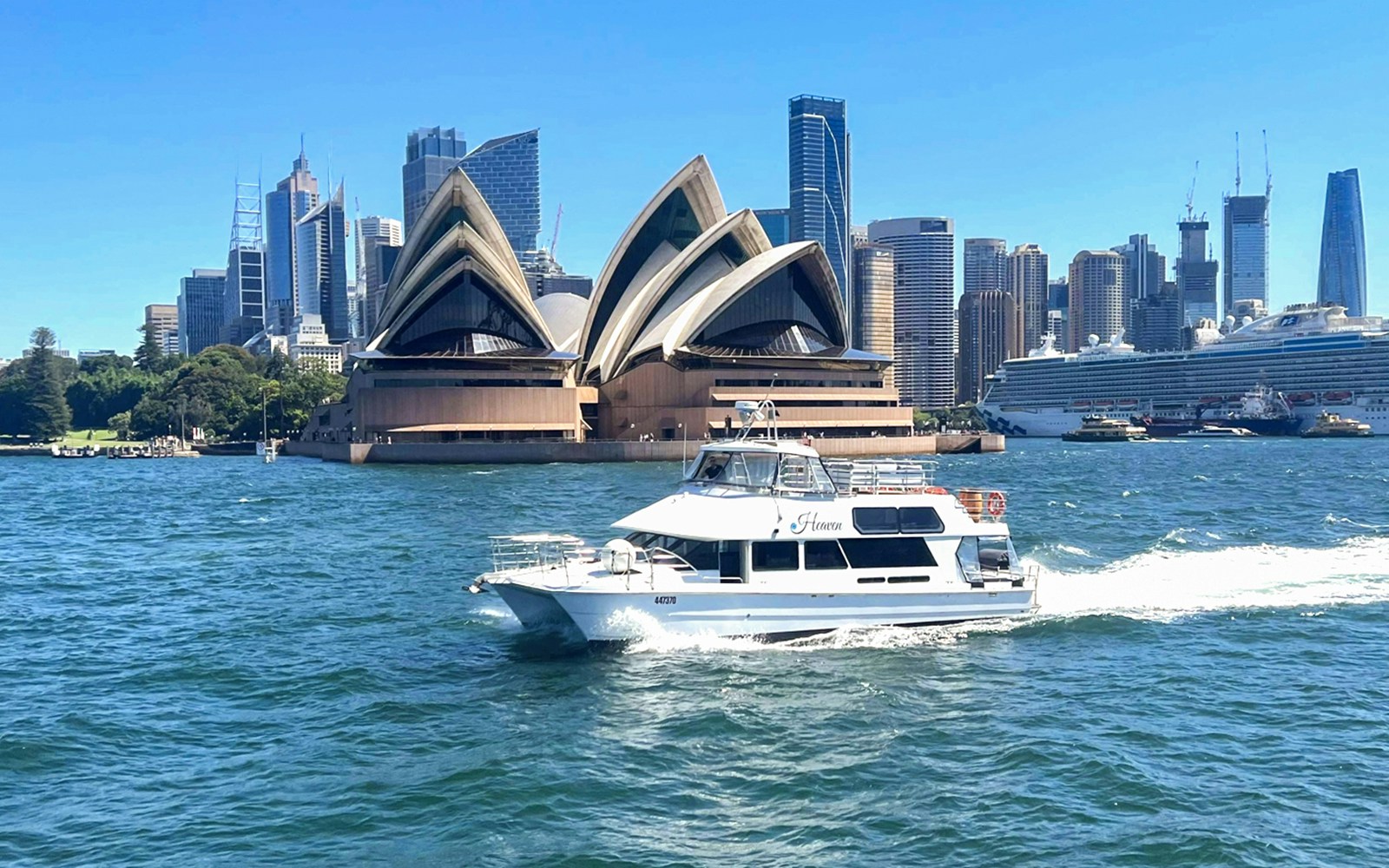 Sydney Harbour cruise ship sailing past the Sydney Opera House at sunset.