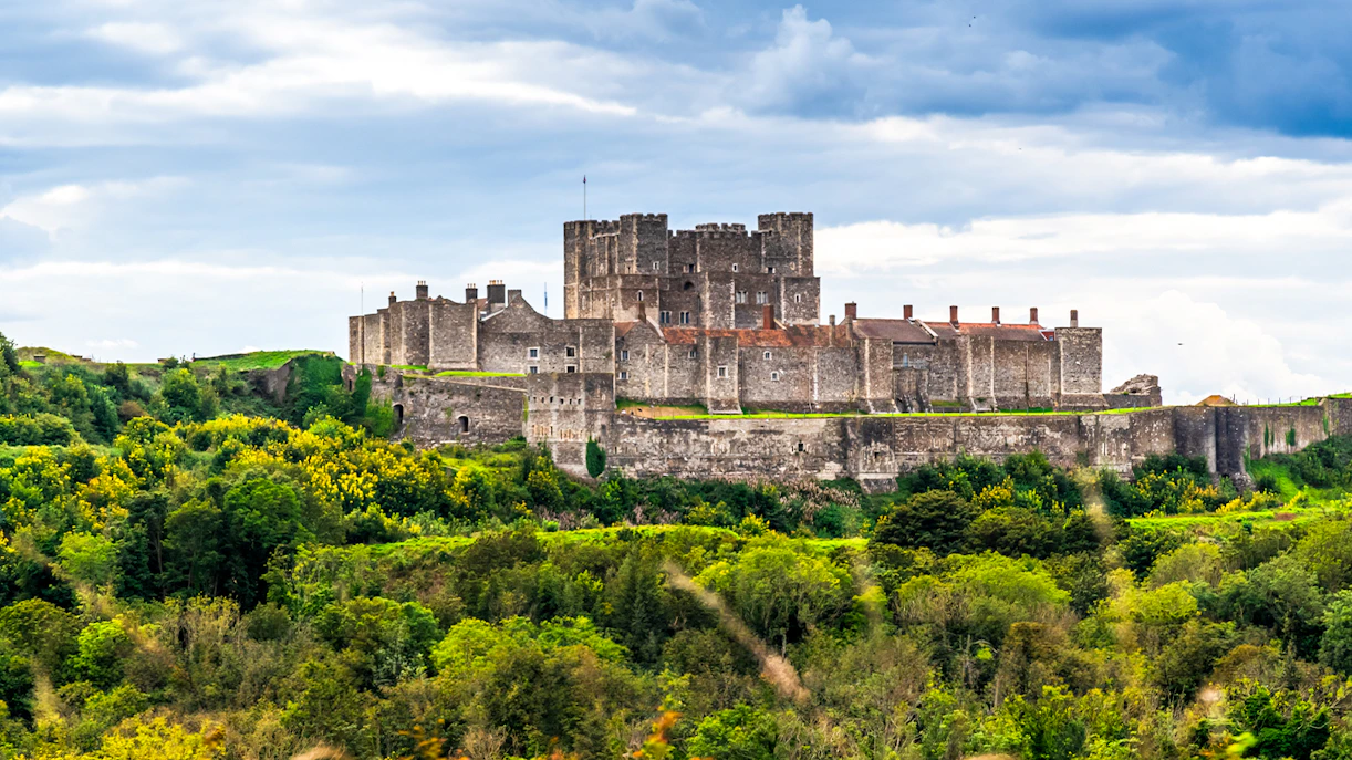 Dover Castle surrounded by lush greenery under a cloudy sky.