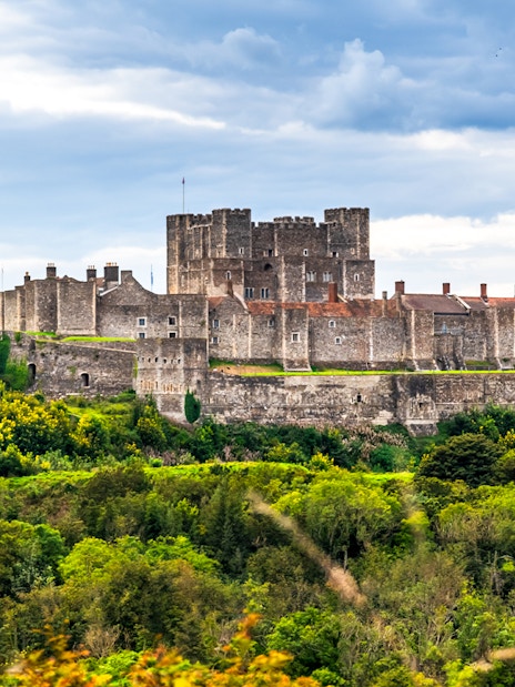 Dover Castle surrounded by lush greenery under a cloudy sky.