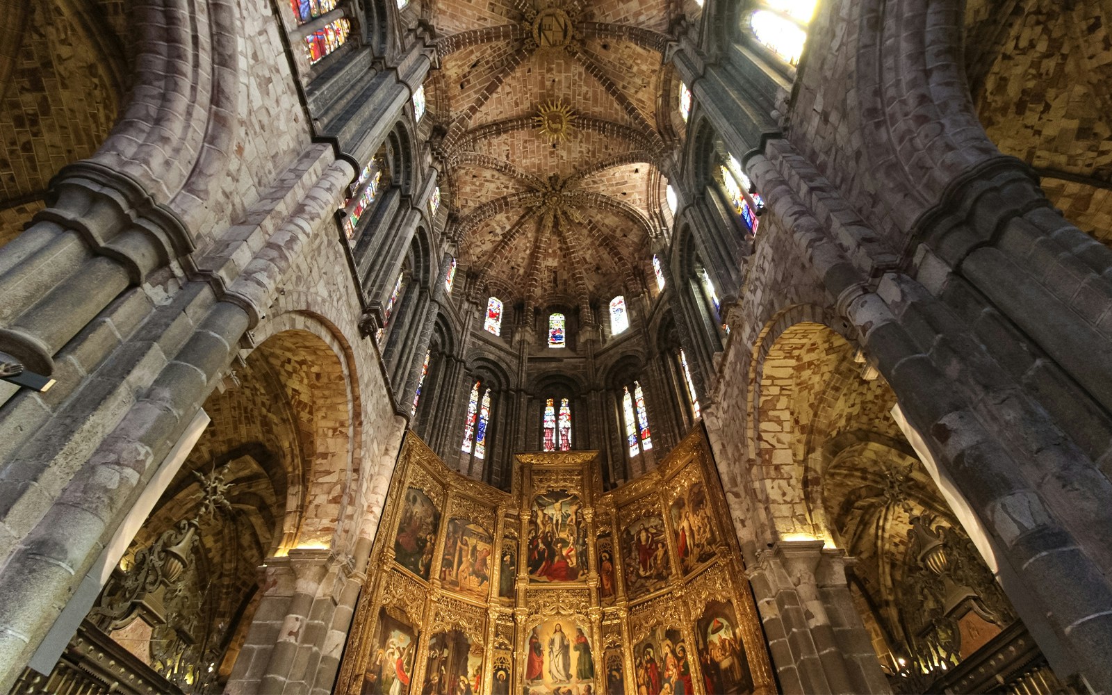 Ávila Cathedral interior with intricate stone arches and stained glass windows.