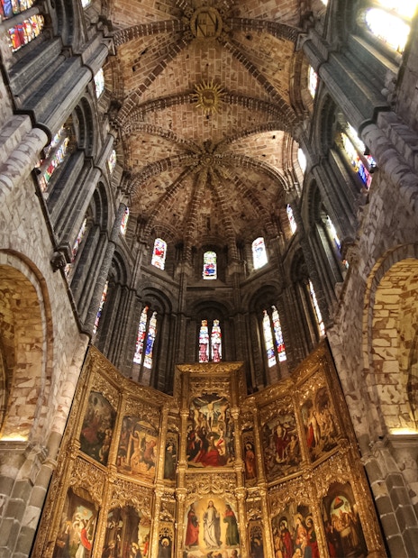 Ávila Cathedral interior with intricate stone arches and stained glass windows.