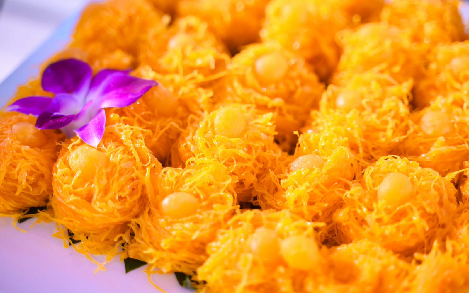 Golden desserts with purple orchid garnish on Smile Riverside Dinner Cruise buffet.